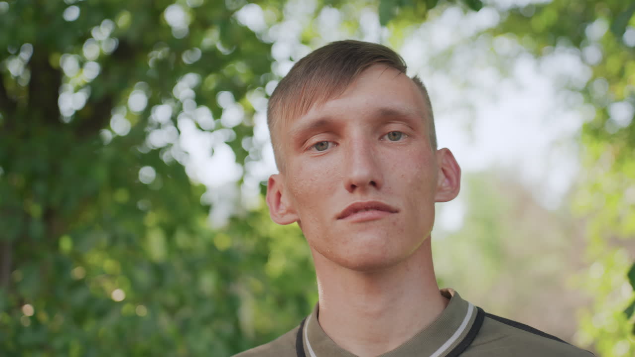 Young White Man In Leafy Park, Wearing Sunglasses And Scanning Surroundings With Tense, Guarded Expression Afternoon Sunlight Filters Through Leaves, Mossy Tree Trunks, Soft Breeze, Cinematic Shallow