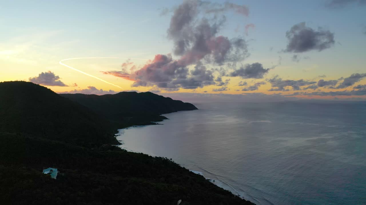 Warm, colorful skies paint the horizon over St. Croix’s ocean and forested peninsula, captured by drone in the soft early morning light of a tranquil Caribbean day