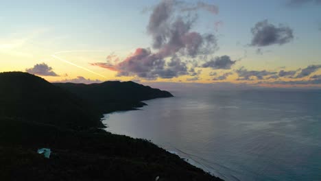 warm, colorful skies paint the horizon over st. croix’s ocean and forested peninsula, captured by drone in the soft early morning light of a tranquil caribbean day