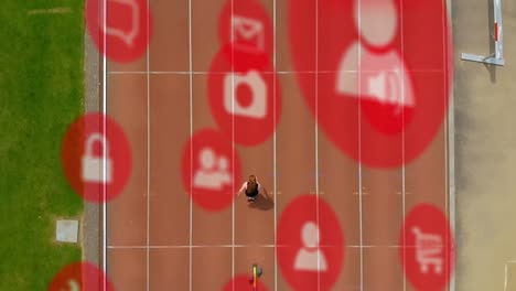 Animation-of-multiple-icons-over-aerial-view-of-caucasian-woman-running-on-race-track