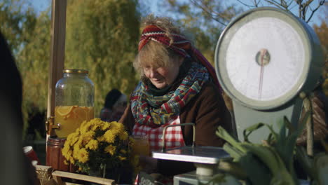elderly saleswoman stands at the stall elderly saleswoman stands at the stall gives honey to taste people pay for a jar of honey with cash local farmers market or autumn fair outdoors vegetarian and organic food agriculture