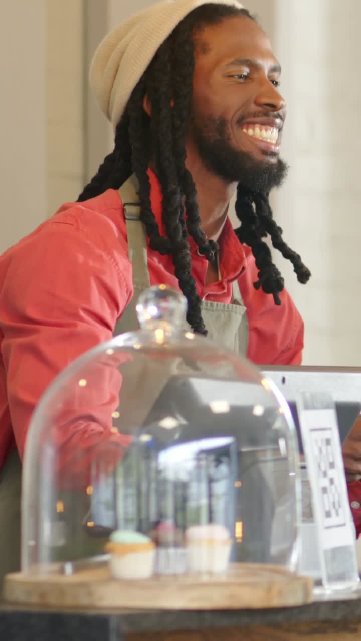 Vertical video: Order arriving barista at cafe in apron using POS and handing cupcakes in dome