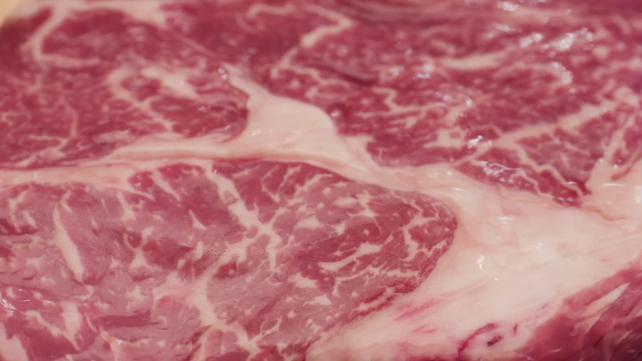 Fresh marbled beef with pepper, salt and rosemary close-up macro. Preparation to cook juicy steak on grill. Premium organic raw wagyu meat. High quality 4k footage