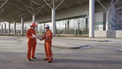 travailleurs de la construction en uniforme orange et casques regardant ensemble sur les plans 1