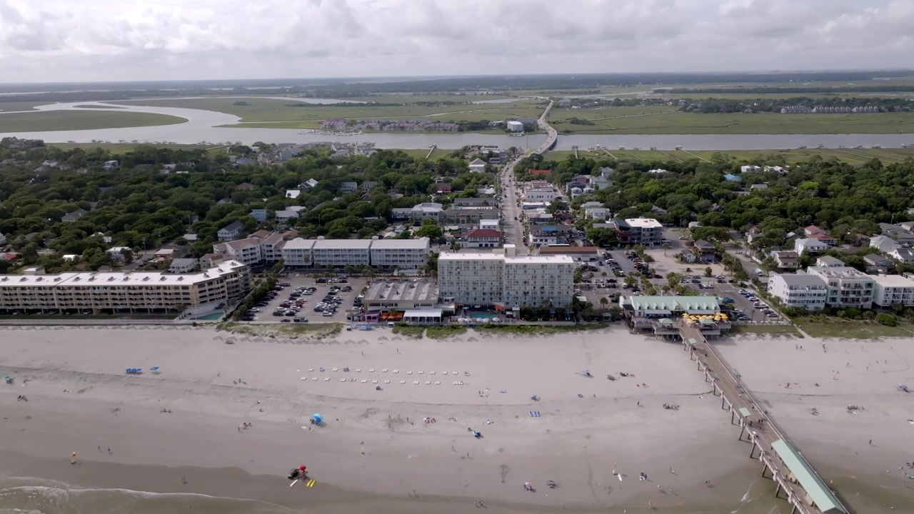 Folly Beach i South Carolina med strandudsigt, hoteller, turister og en mole, med dronevideo, der bevæger sig fra venstre mod højre