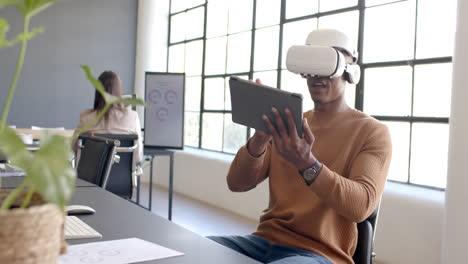 using vr headset, african american man interacting with tablet in modern office setting