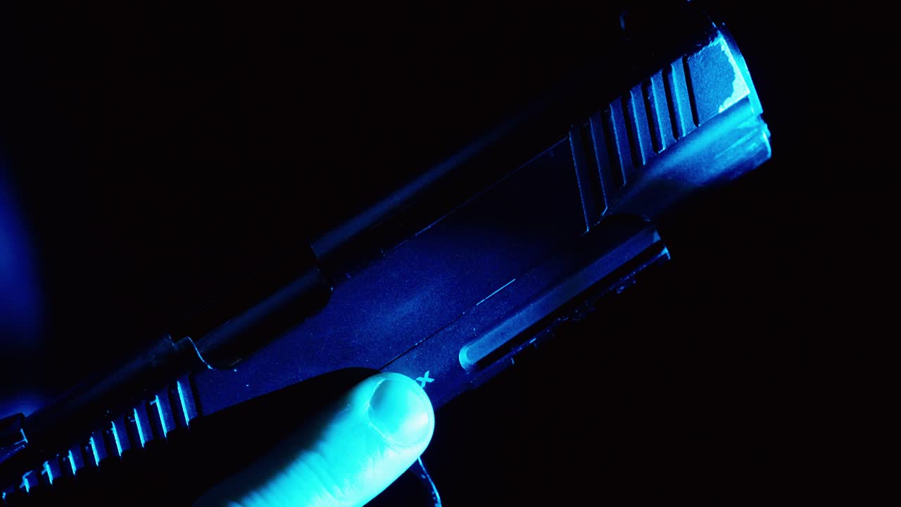 Cinematic close-up of a hand loading a pistol under blue light, symbolizing danger, tension, and a high-risk situation