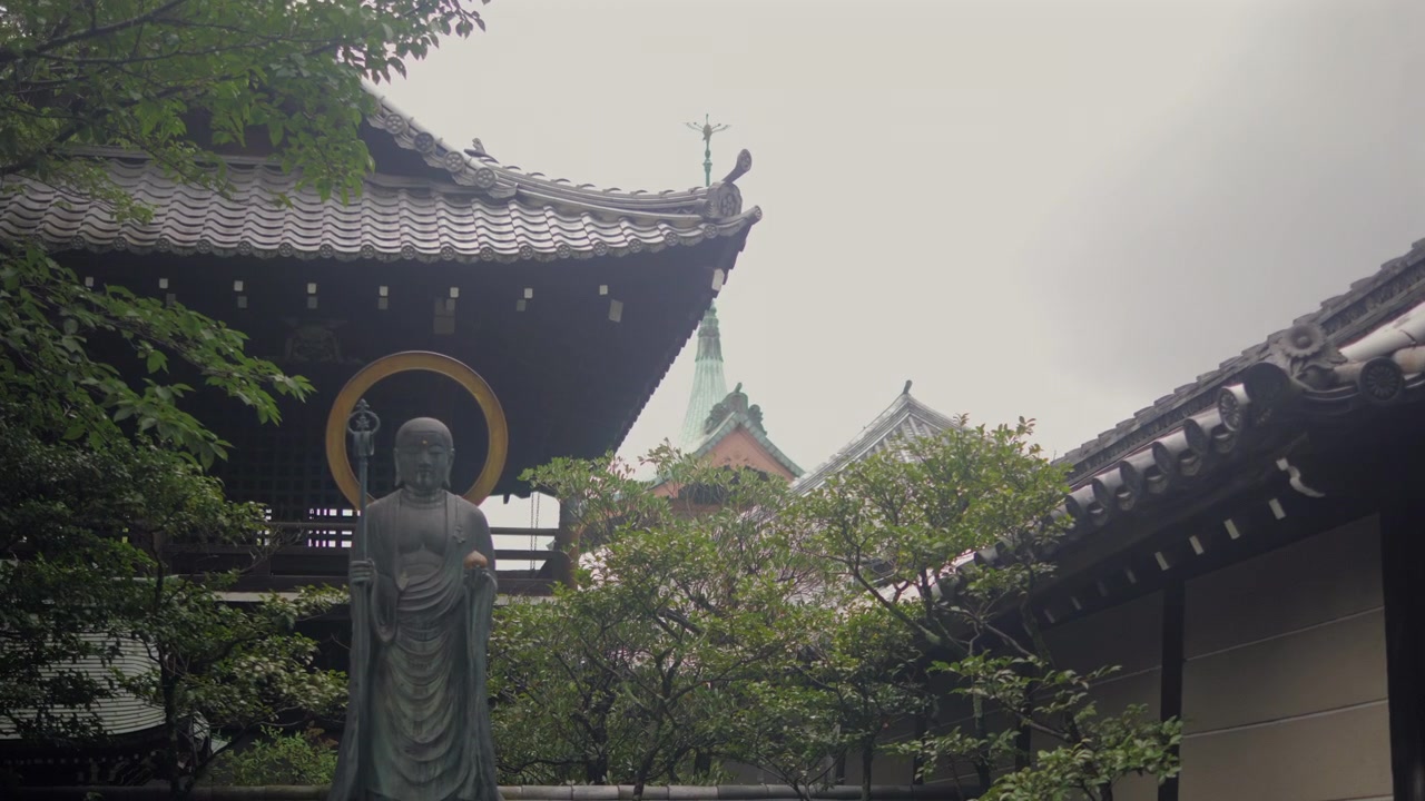 Statua buddista si erge nel cortile del tempio con tetti tradizionali a Kyoto, Giappone.