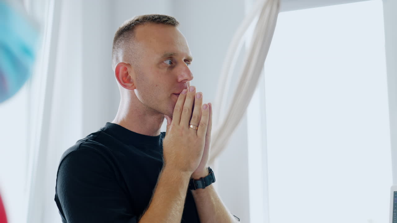Man is holding hands in front of his face in praying position. Worried husband portrait during the childbirth of his baby in hospital ward.