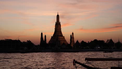 time-lapse of a boat passing by wat arun at sunset