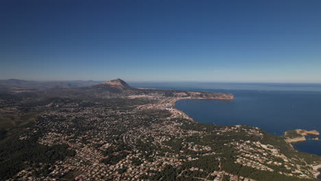 aerial view of javea coastline in alicante with dolly forward, tilt down over housing development