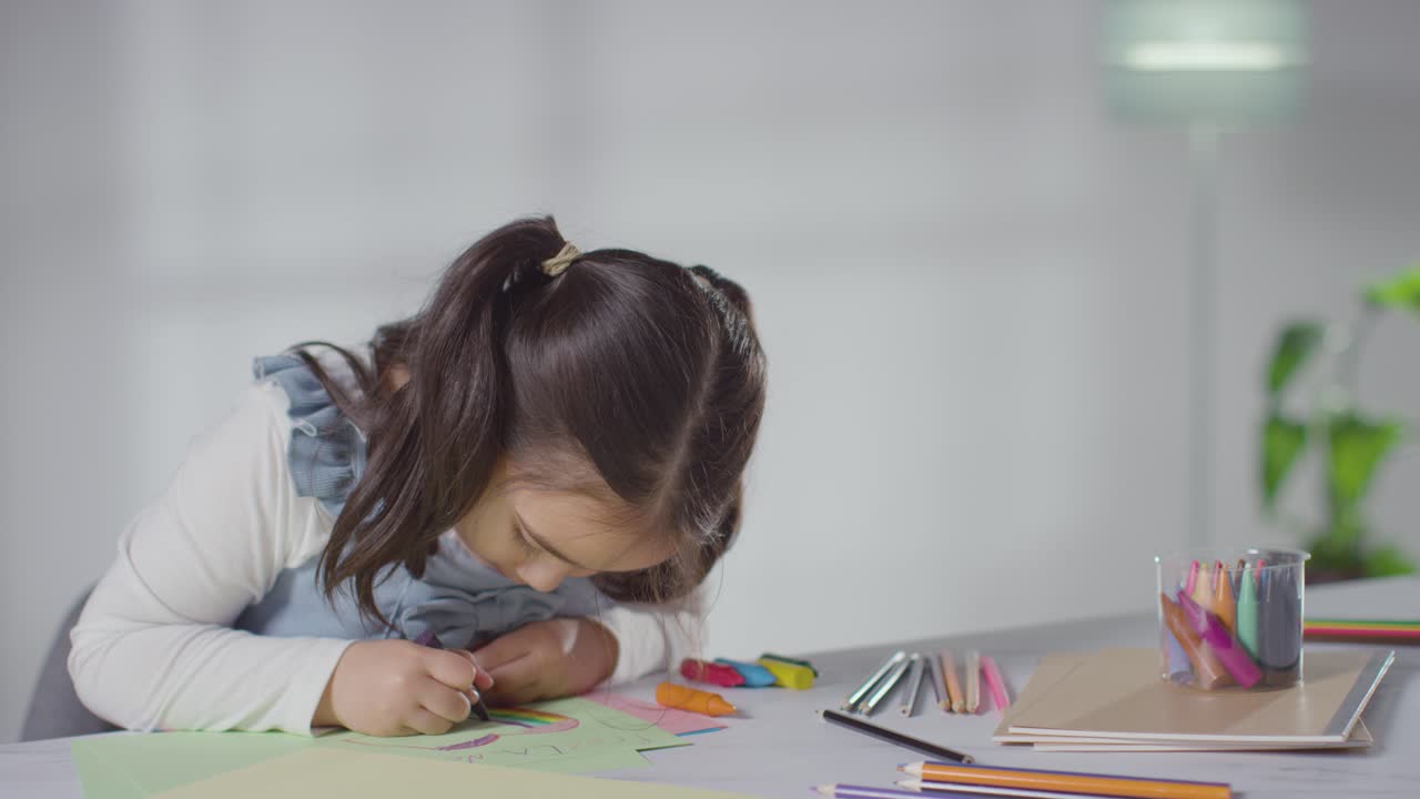 foto de una niña en la mesa en casa dibujando y coloreando una imagen