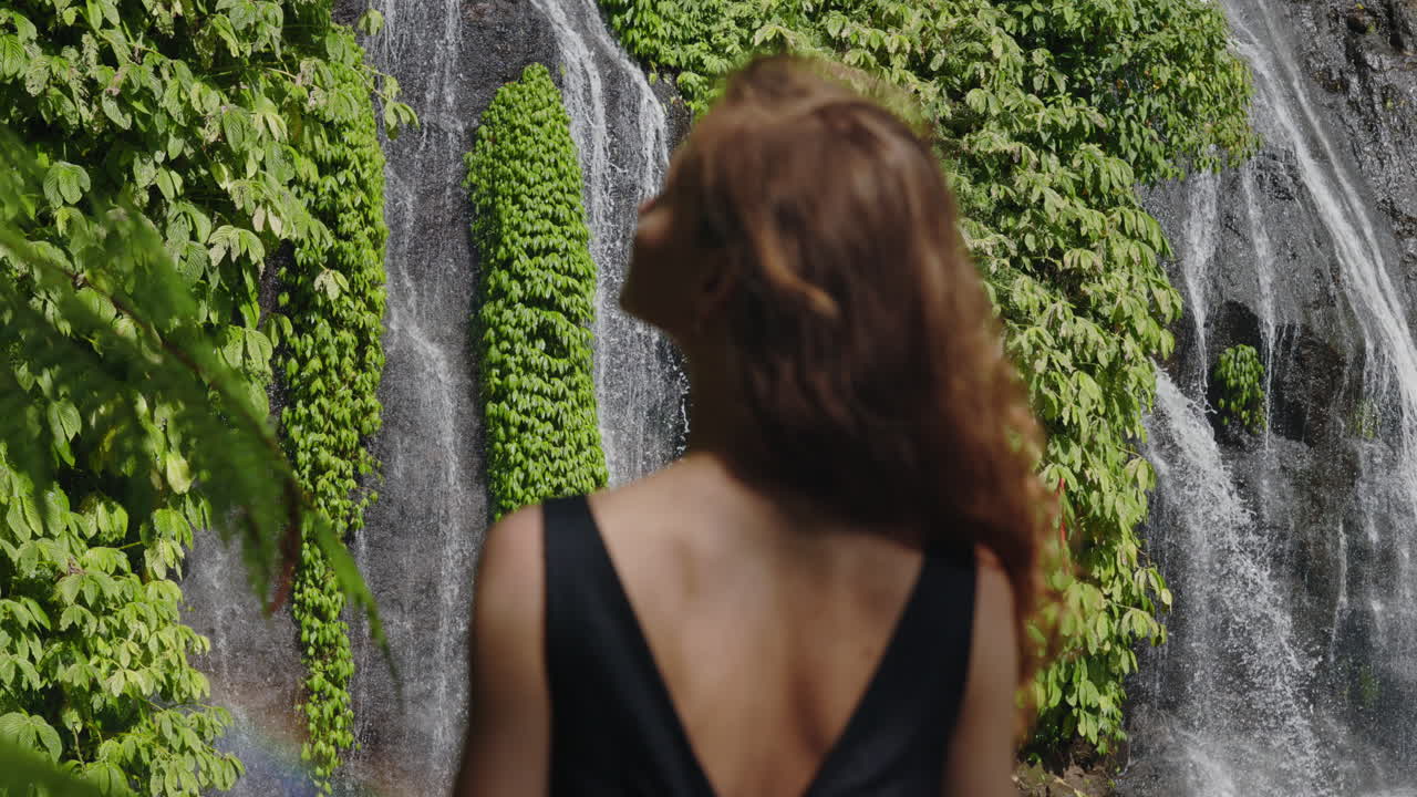 Femme admirant la vue d'une cascade tropicale luxuriante.