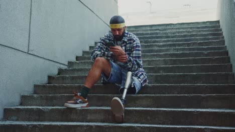 man with prosthetic leg using smartphone on stairs
