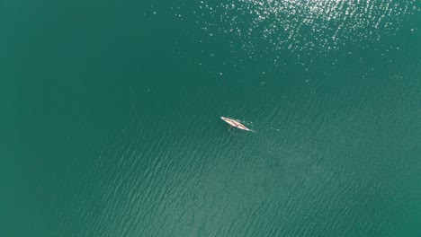 Aerial-top-down,-kayaker-paddling-on-a-turquoise-lake-on-a-sunny-summer-day