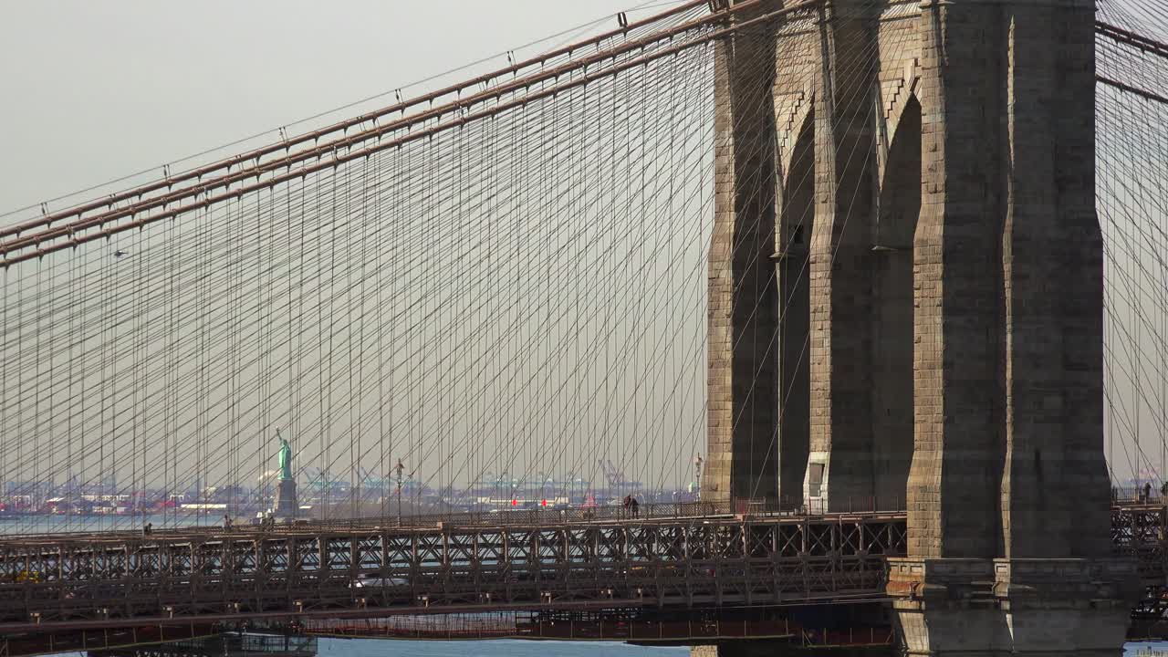 Una vista attraverso il Ponte di Brooklyn con la Statua della Libertà in lontananza