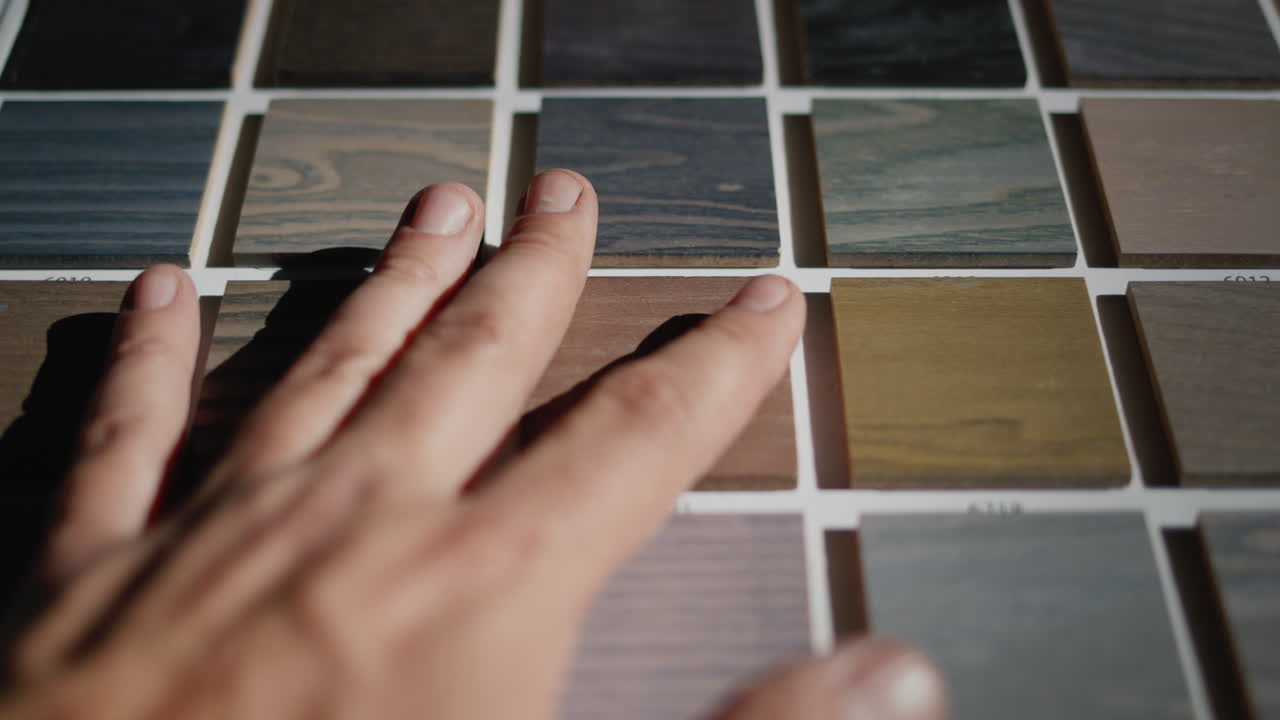 The designer's hand runs his fingertips over the painted wood samples. Renovation and design in the house concept