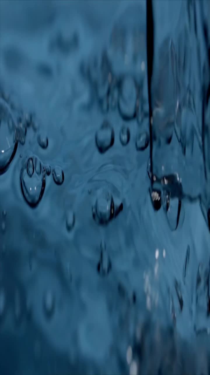 Nahaufnahme von klarem Wasser, das in blaue Flüssigkeit mit Blasen fließt