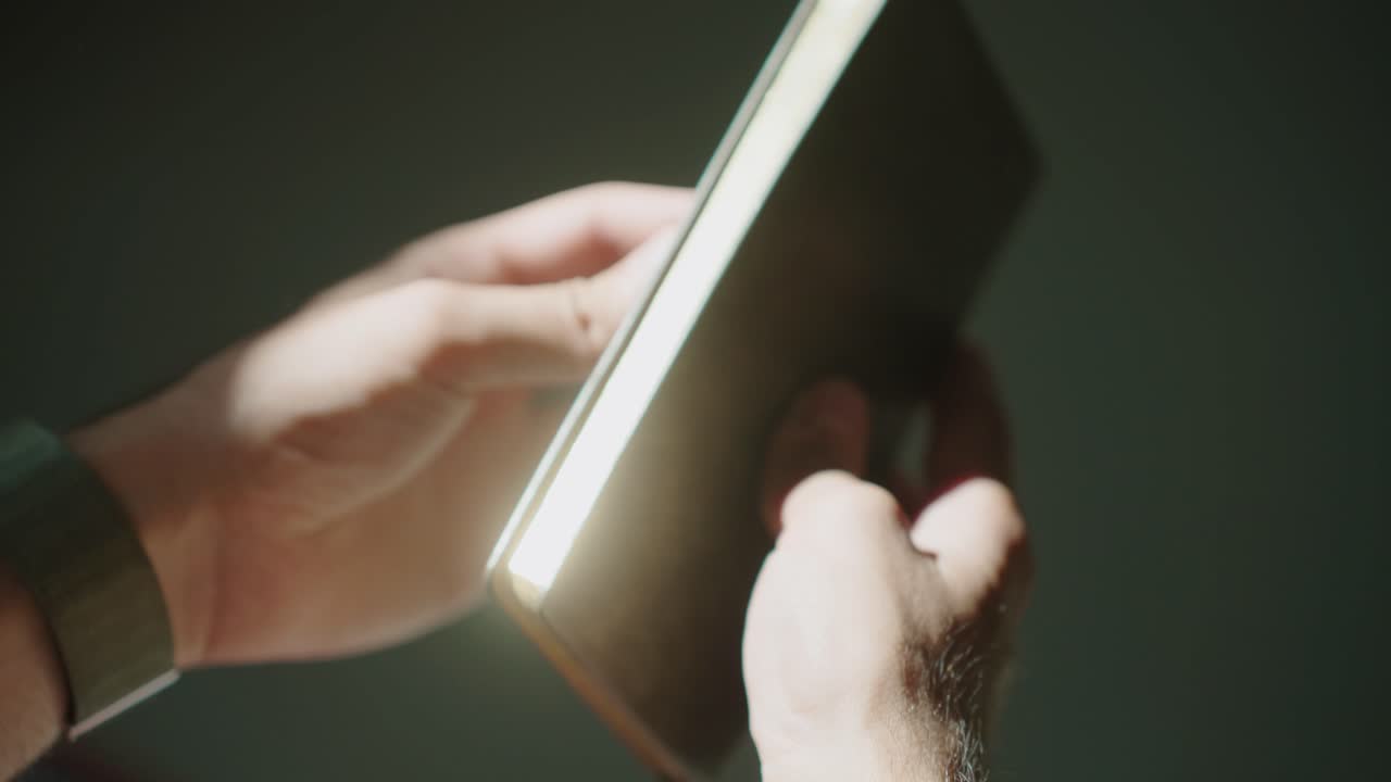 Hands hold and examine an old book in soft lighting, nostalgic mood