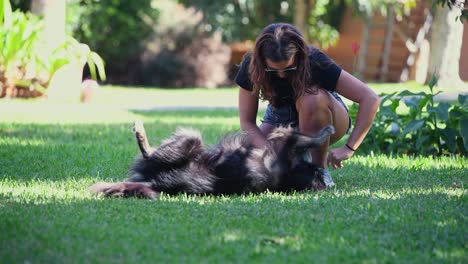 Eine-Junge-Kaukasische-Frau-Spielt-An-Einem-Sonnigen-Tag-Mit-Ihrem-Schwarzen-Hund-Im-Garten-Eines-Hauses