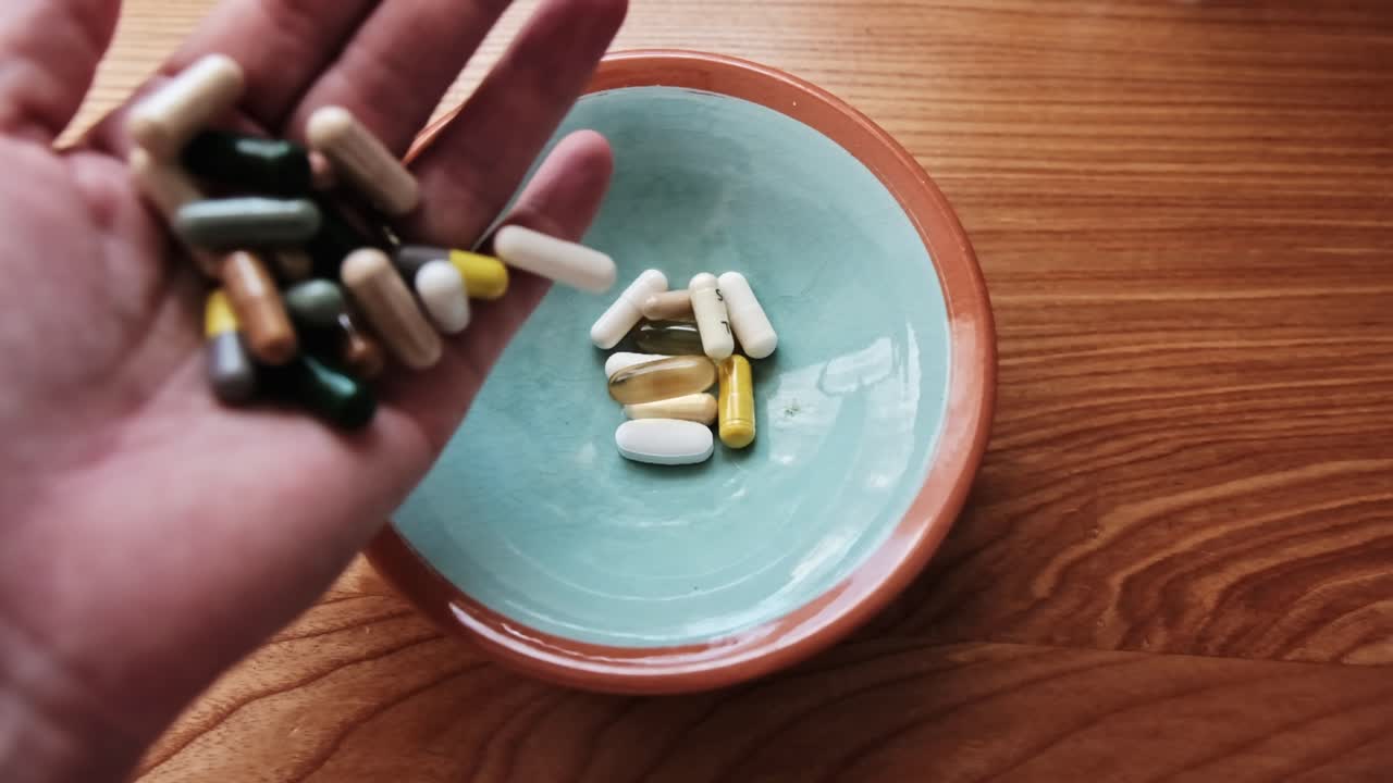 Hand Pouring Assorted Pills into a Bowl