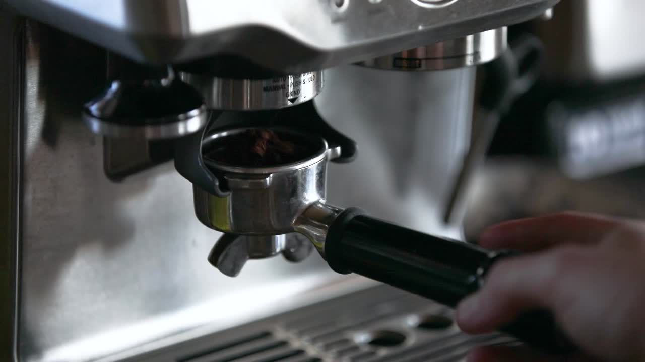 un hombre comienza a moler granos de espresso en una máquina de espresso automática en 1080p 60fps