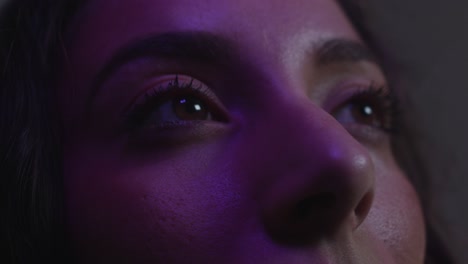 close up on eyes looking up to a screen colours change on woman's face