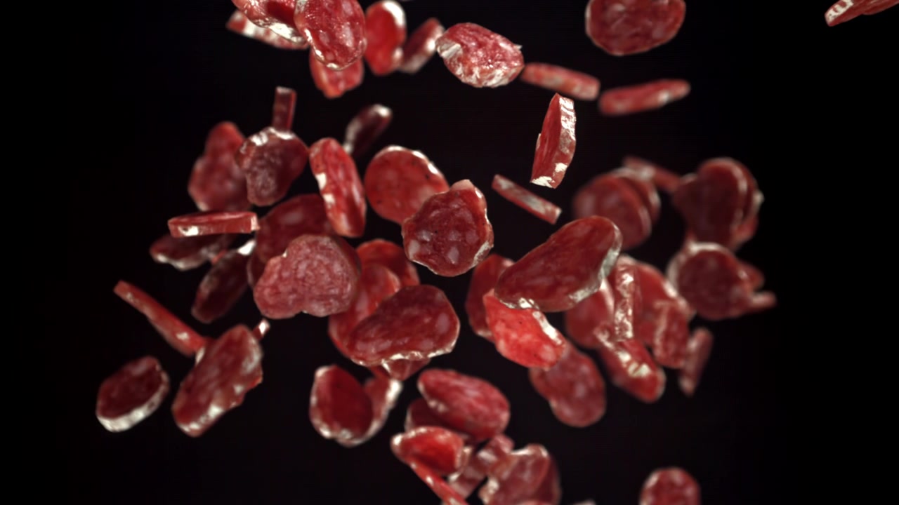 Fette di salame che cadono al rallentatore su sfondo nero