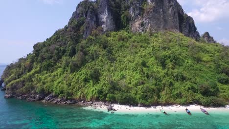 Extraordinary-aerial-shot-of-traditional-Thai-boats-on-the-shore-of-a-private-beach-on-a-mountainous-exotic-island