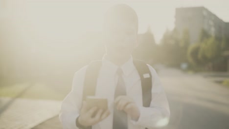 CU-Tracking-Portrait-of-schoolboy-boy-with-knapsack-behind-his-back-in-school-uniform