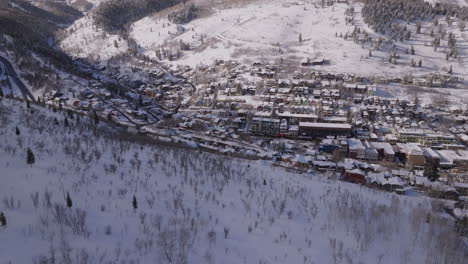 Beautiful-Aerial-Drone-Shot-Pushing-over-Mountain-to-Reveal-Park-City,-Utah,-on-a-Sunny-Day-in-Winter,-4K