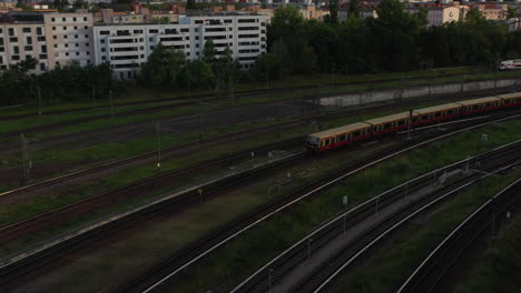 Pan-and-tilt-footage-of-regional-train-driving-on-turning-railway-tracks-in-evening-holden-hour-sun-light.-Berlin,-Germany