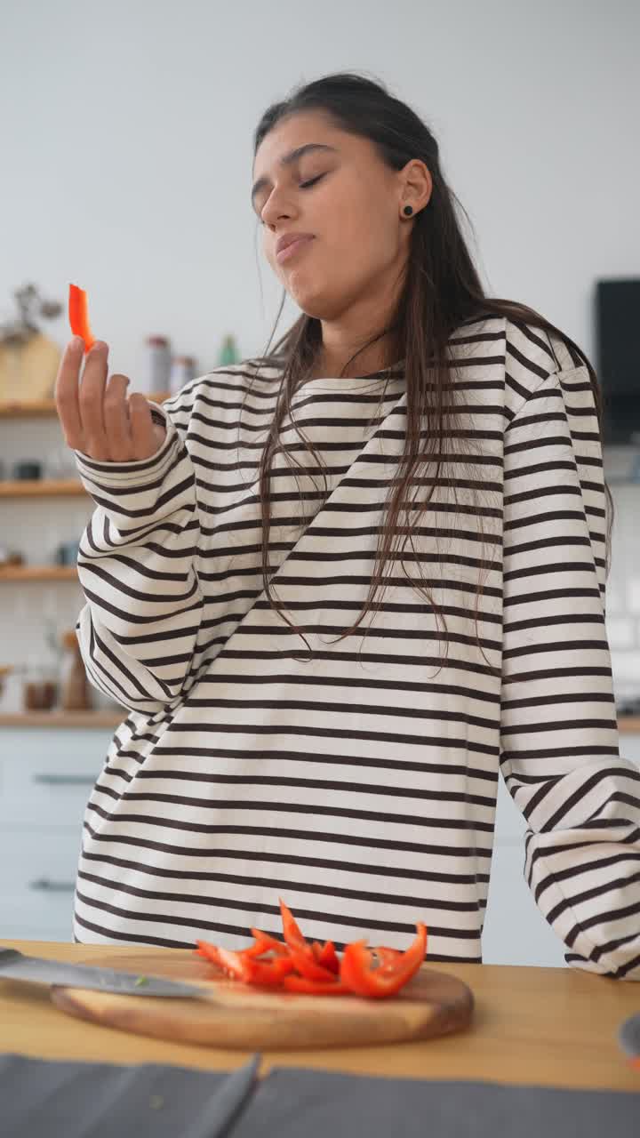 mujer comprobando pimienta roja en rebanadas en la cocina