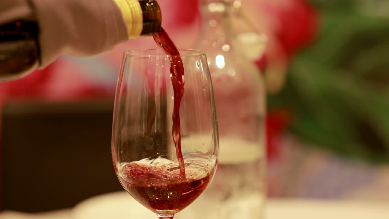 A sequence of red wine being poured into a glass, highlighting the elegance of fine dining with soft lighting