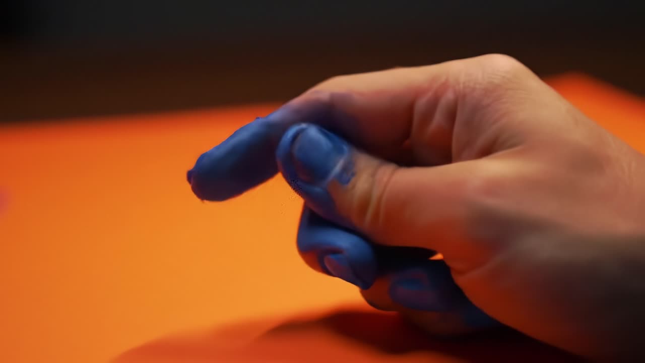 A Creative Exploration of Colorful Finger Painting with Vivid Blue Paint on an Orange Background Showcasing Artistic Techniques in Progress