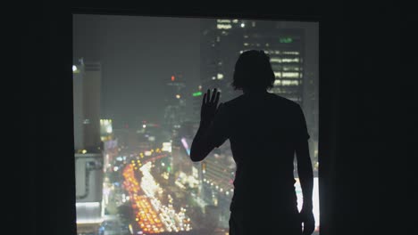 silhouetted man looking out of window