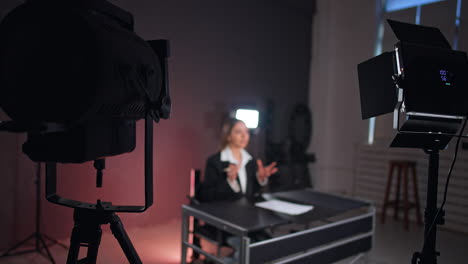 back view of the soffits lighting the lady sitting and talking at desk. studio footage of program or podcast.