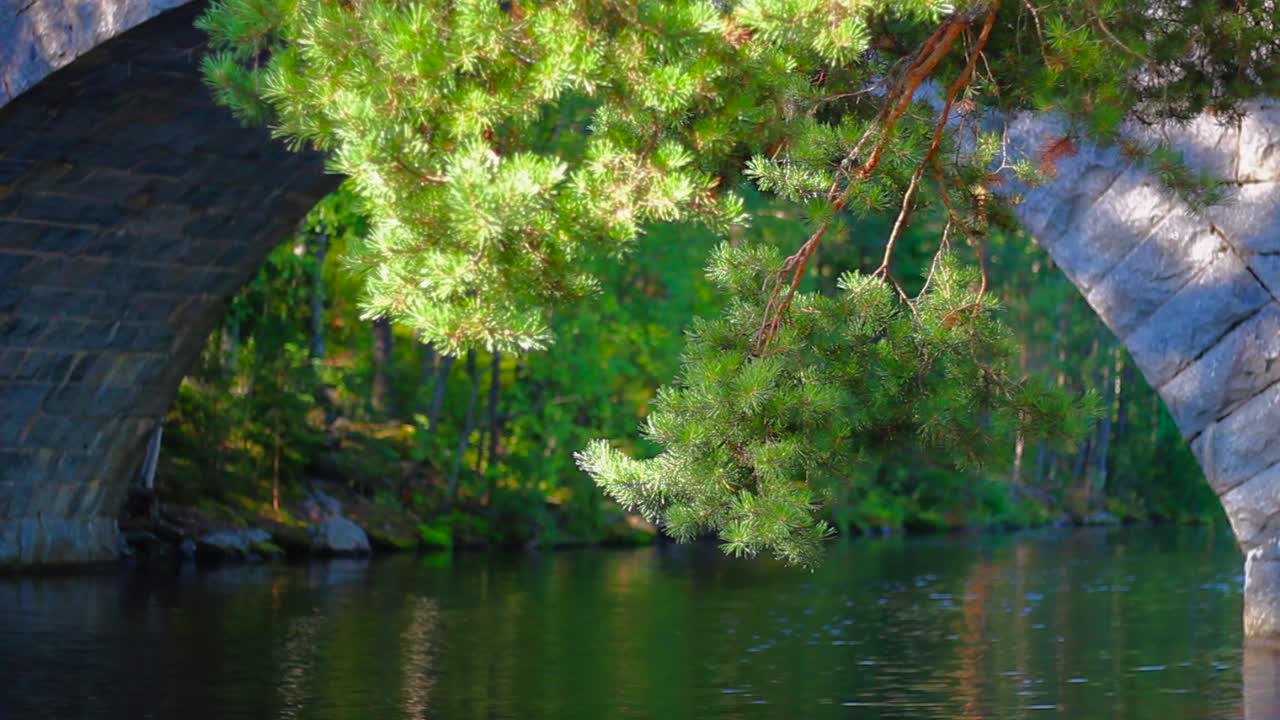 핀란드 여름 동안 오래된 돌다리 아래를 흐르는 잔잔한 강