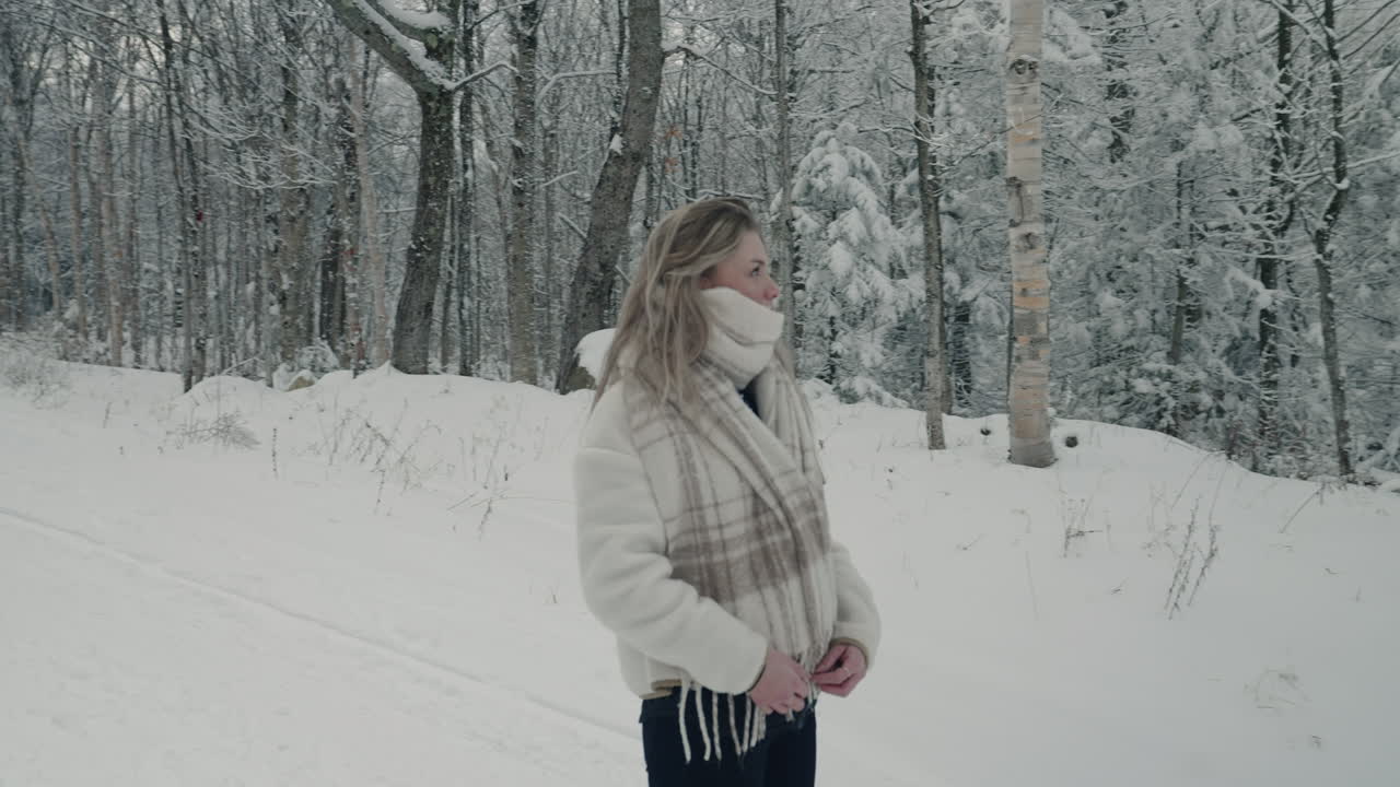 mujer mirando alrededor de árboles desnudos cubiertos de nieve en un camino rural de invierno en orford, quebec, canadá - plano medio
