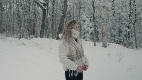 woman looking around snow covered bare trees on a rural winter road in orford, quebec, canada - medium shot