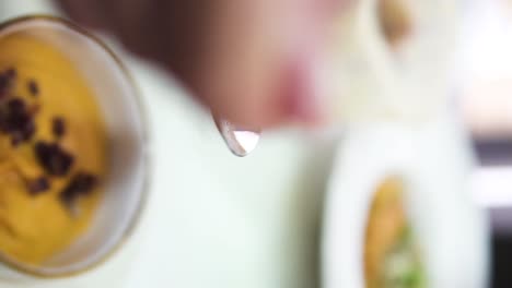 tiro vertical de una cuchara con mantequilla caliente vertida en una deliciosa sopa con trozos de carne en el fondo otros platos en platos en el restaurante