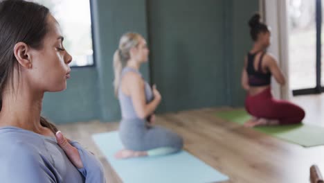 diverse women with hands on chest and stomach practicing breathing exercise in class