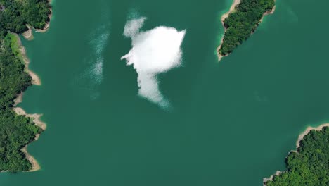 Aerial-top-down-shot-of-natural-lake-with-green-islands-and-sun-reflection-on-water-surface