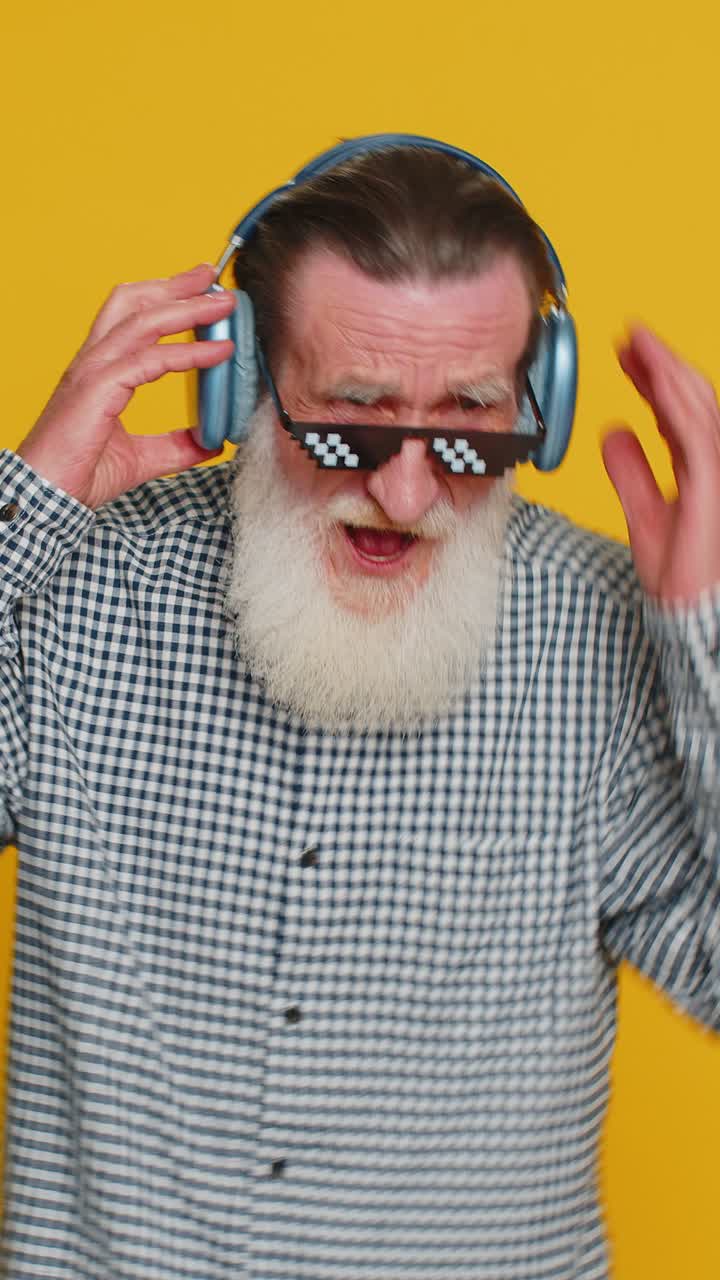 anciano sénior elegante escuchando música a través de auriculares y bailando abuelo jubilado feliz