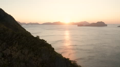 aerial flying backwards showing island around el nido with sunset, palawan, philippines