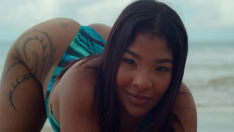 with the sun-kissed sands of las cuevas beach beneath her feet, a young girl in a thong bikini kneel in the sand