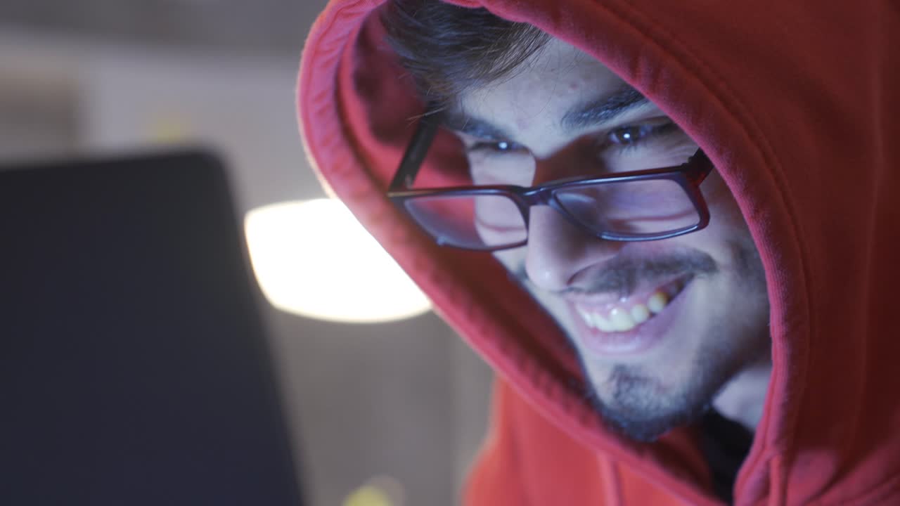 primer plano de un joven trabajando en una computadora portátil por la noche.