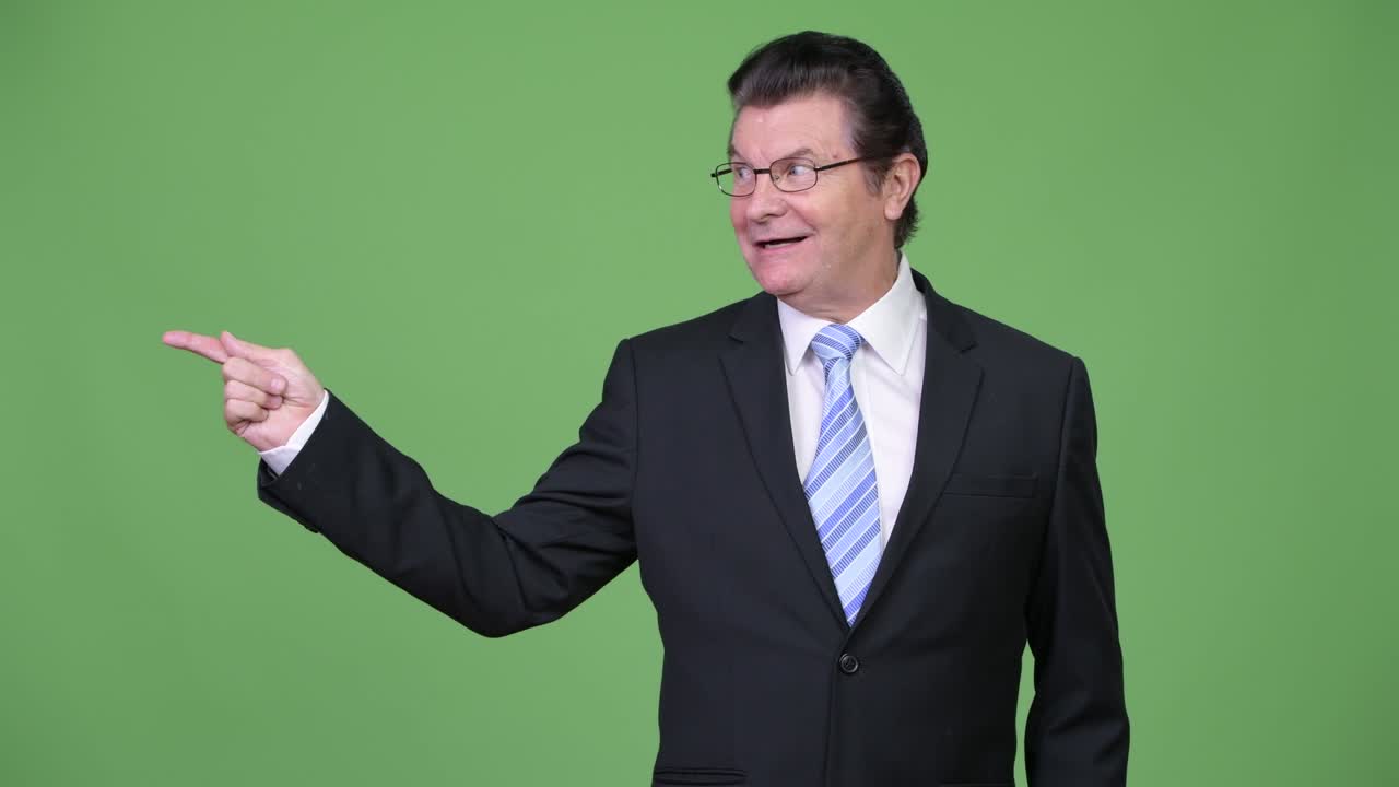 Senior handsome businessman pointing to the side