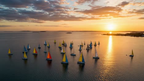 a stunning aerial view of multiple colorful sailboats on calm waters during a breathtaking sunset, showcasing the beauty of nature and sailing activities