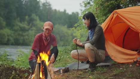 female tourists keeping campfire burning
